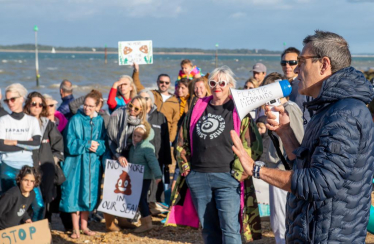 Bob Seely MP speaks with a microphone at the Gurnard Sewage Protests